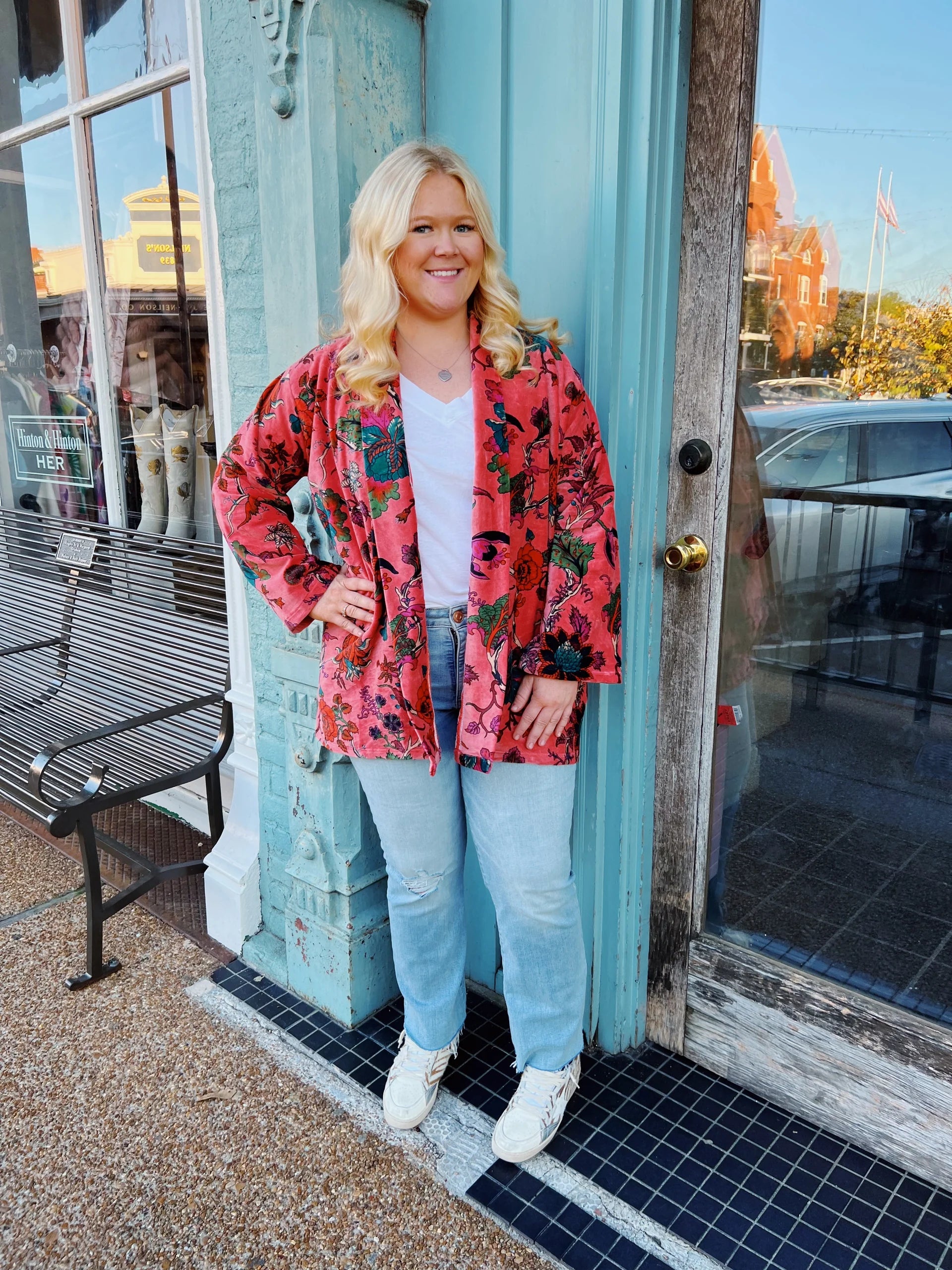 Woman wearing a colorful jacket standing outside a building with a blue door.